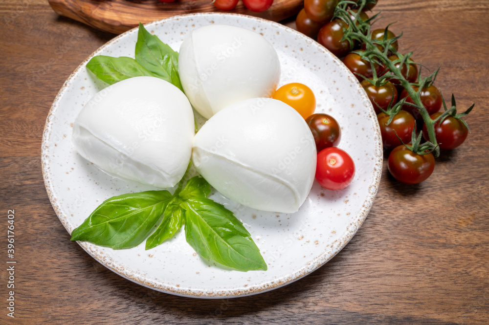 Cheese collection, white balls of soft Italian cheese mozzarella, served with red cherry tomatoes, fresh basil leaves Cheese collection, white balls of soft Italian cheese mozzarella, served with red cherry tomatoes, fresh basil leaves