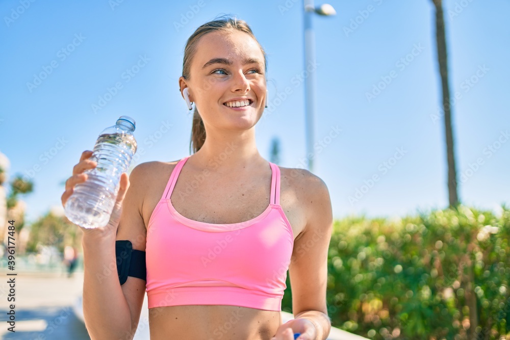 Young blonde sportswoman doing exercise drinking bottle of water at the city Young blonde sportswoman doing exercise drinking bottle of water at the city
