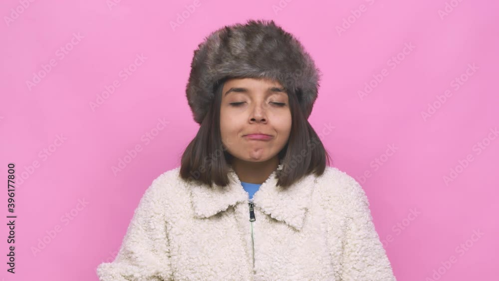 Young hispanic woman wearing a winter hat face closeup surprised pointing with finger, smiling broadly Young hispanic woman wearing a winter hat face closeup surprised pointing with finger, smiling broadly