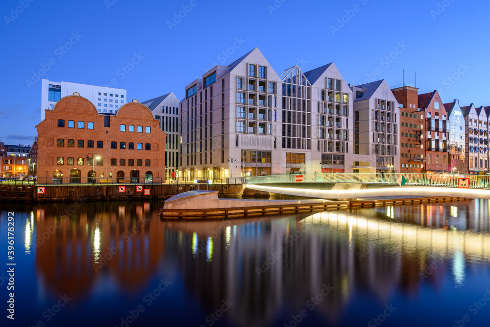 Footbridge over the Motlawa River and modern architecture of Granaries Island in Gdansk at night. Poland