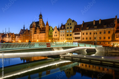 Footbridge over the Motlawa River and historic architecture of Gdansk Old Town at night. Poland