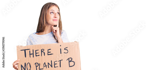 Young beautiful blonde woman holding there is no planet b banner serious face thinking about question with hand on chin, thoughtful about confusing idea