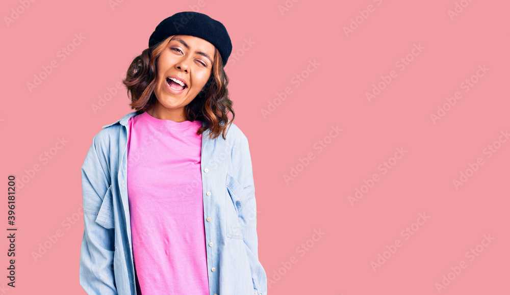 Young beautiful mixed race woman wearing french look with beret winking looking at the camera with sexy expression, cheerful and happy face. Young beautiful mixed race woman wearing french look with beret winking looking at the camera with sexy expression, cheerful and happy face.