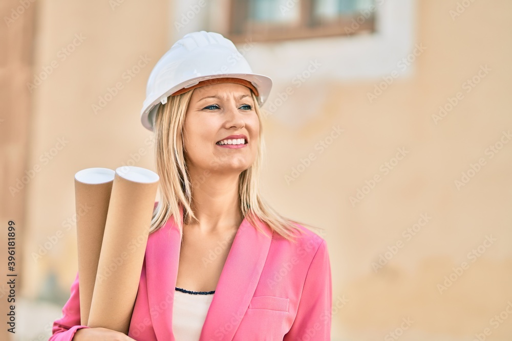 Young caucasian architect smiling happy holding blueprints standing at the city. Young caucasian architect smiling happy holding blueprints standing at the city.