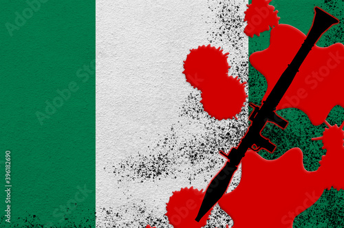 Nigeria flag and black RPG-7 rocket-propelled grenade launcher in red blood. Concept for terror attack or military operations with lethal outcome photo