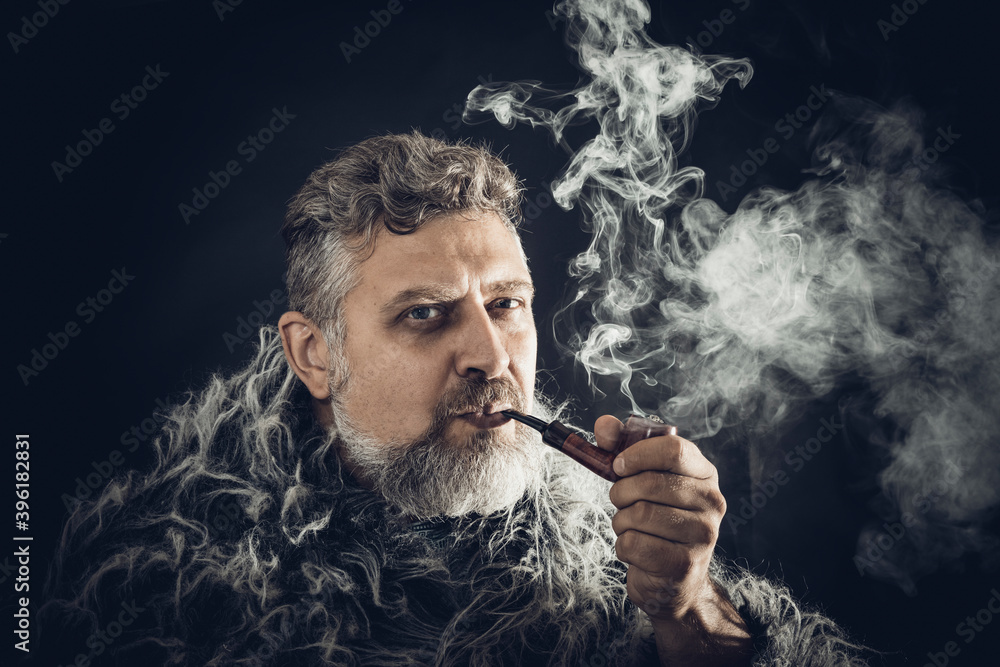 Obraz premium Solid bearded man in a fur mantle smoking pipe