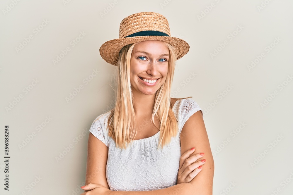 Young blonde girl wearing summer hat happy face smiling with crossed arms looking at the camera. positive person. Young blonde girl wearing summer hat happy face smiling with crossed arms looking at the camera. positive person.