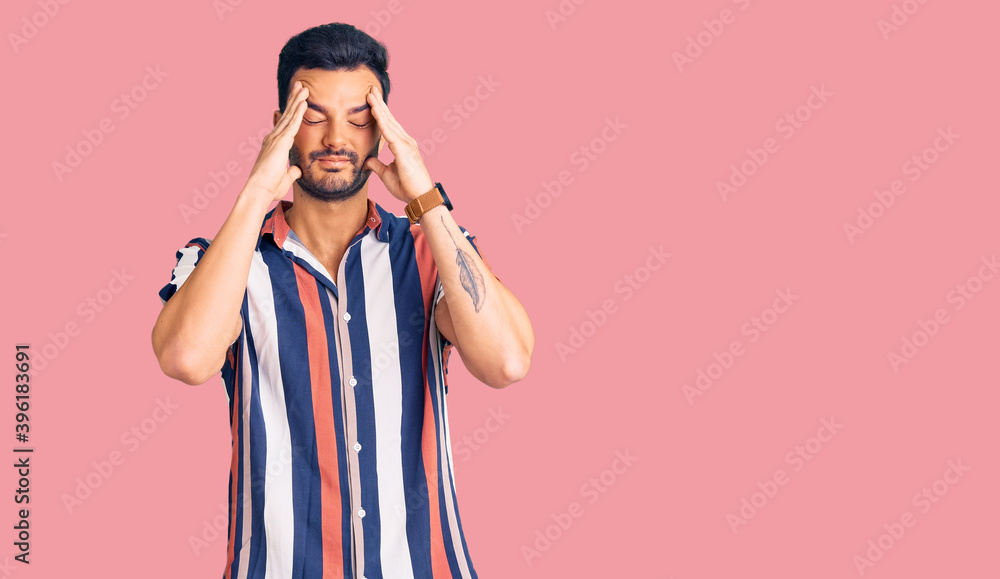 Young handsome hispanic man wearing casual summer shirt suffering from headache desperate and stressed because pain and migraine. hands on head. Young handsome hispanic man wearing casual summer shirt suffering from headache desperate and stressed because pain and migraine. hands on head.