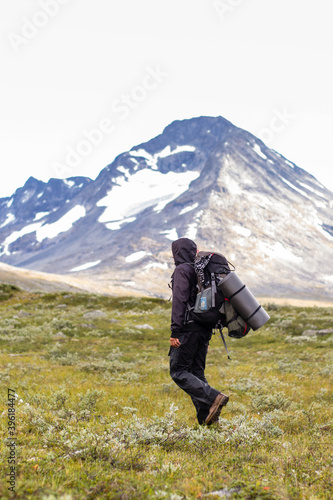 Male backpacker going through meadow, with stunning snowy mountains in background