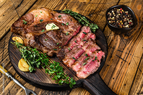 Roast rib eye beef meat steak on a cutting board. wooden background. Top view