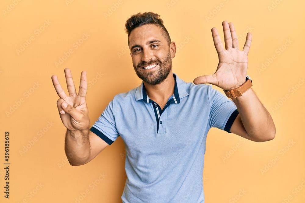 Handsome man with beard wearing casual clothes showing and pointing up with fingers number eight while smiling confident and happy. Handsome man with beard wearing casual clothes showing and pointing up with fingers number eight while smiling confident and happy.
