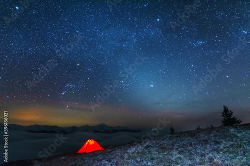 Space starry nights with a bright Milky Way on the backdrop of tourists with tents.