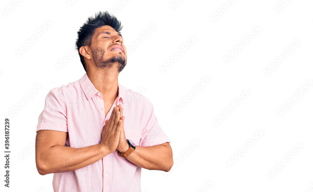 Handsome latin american young man wearing casual summer shirt begging and praying with hands together with hope expression on face very emotional and worried. begging. Handsome latin american young man wearing casual summer shirt begging and praying with hands together with hope expression on face very emotional and worried. begging.