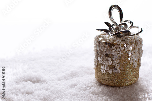 Cylindrical Christmas toy. Christmas tree toy with gold spangles in the snow. Horizontal orientation. Copy space. Empty space for text