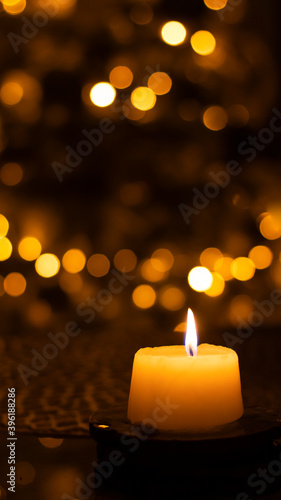 A candle burns against a blurred golden bokeh background. Close-up, blurred background. Festive New Year background.