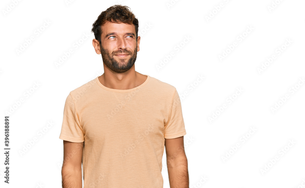 Handsome young man with beard wearing casual tshirt smiling looking to the side and staring away thinking. Handsome young man with beard wearing casual tshirt smiling looking to the side and staring away thinking.