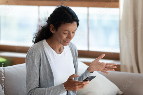 Mad millennial African American woman look at cellphone screen feel frustrated by virus or spam. Unhappy angry young biracial female user or client confused by operational problem on smartphone. Free Download Mad millennial African American woman look at cellphone screen feel frustrated by virus or spam. Unhappy angry young biracial female user or client confused by operational problem on smartphone. - GFXLoad