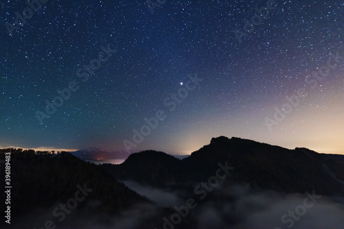 A beautiful starry night in the mountains on top with beautiful scenery and fog. 