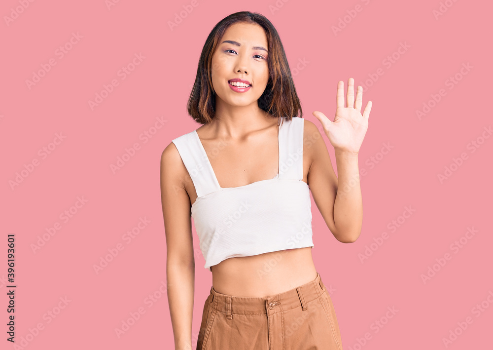Young beautiful chinese girl wearing casual clothes showing and pointing up with fingers number five while smiling confident and happy. Young beautiful chinese girl wearing casual clothes showing and pointing up with fingers number five while smiling confident and happy.