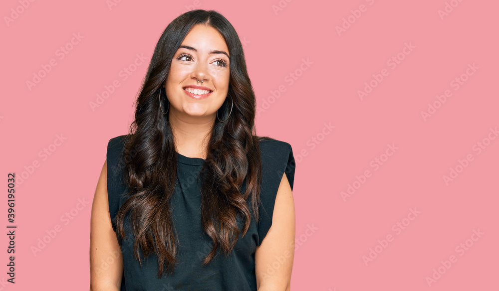 Fototapeta premium Beautiful brunette young woman wearing black shirt looking away to side with smile on face, natural expression. laughing confident.