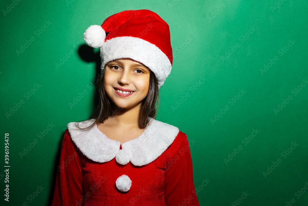 Studio portrait of smile children girl wearing red costume of Santa Claus on green background. Studio portrait of smile children girl wearing red costume of Santa Claus on green background.