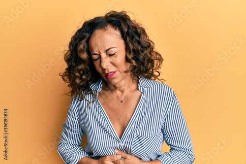 Middle age hispanic woman wearing casual clothes with hand on stomach because indigestion, painful illness feeling unwell. ache concept.