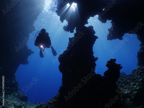 cave diving underwater scuba divers exploring caves ocean scenery sun beams and rays background