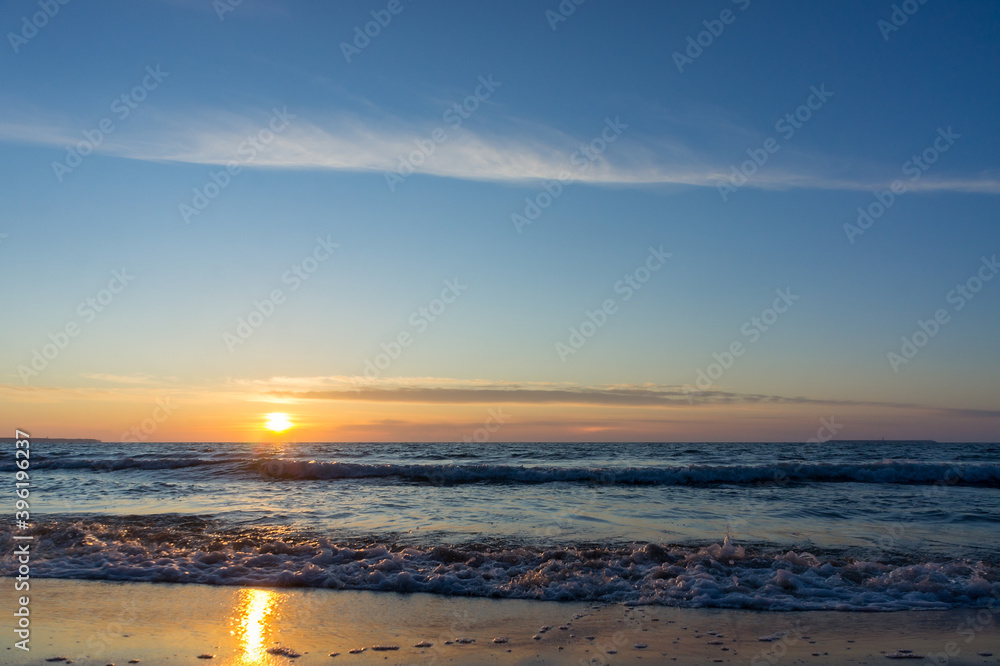 Sunset over the sea. Reflection of sunlight in the sea waves. The sky in the sunset rays. Baltic Sea.