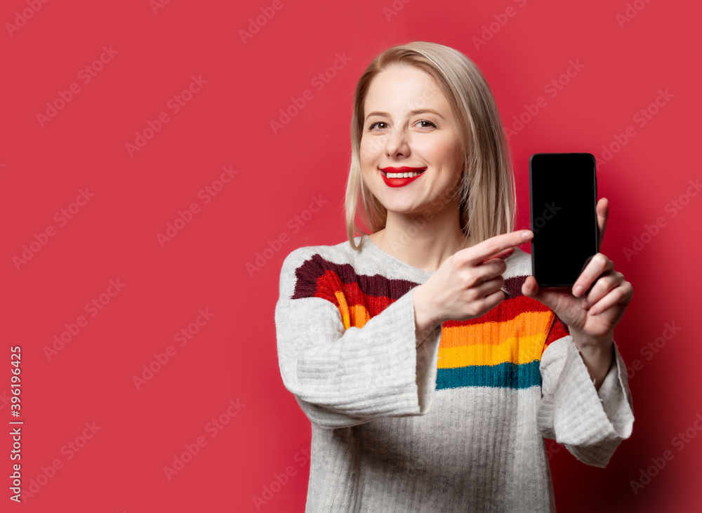Beautiful blonde in sweater with mobile phone on red background Beautiful blonde in sweater with mobile phone on red background