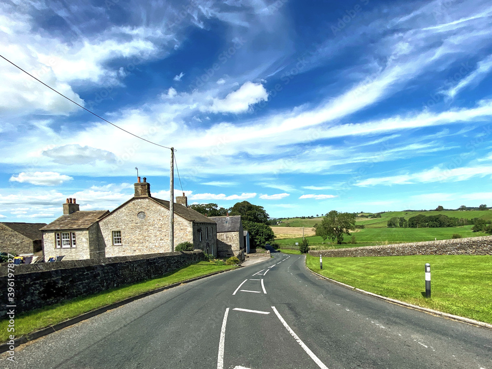 The bottom of, Bracewell Lane, with houses, fields and trees, on a hot day in, Bracewell, Barnoldswick, UK