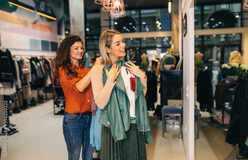 Female seller helps buyer to choose between different clothes.