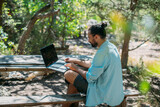 Male tourist working on a laptop outdoors in a camping.
