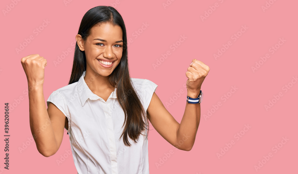 Beautiful hispanic woman wearing casual clothes screaming proud, celebrating victory and success very excited with raised arms Beautiful hispanic woman wearing casual clothes screaming proud, celebrating victory and success very excited with raised arms