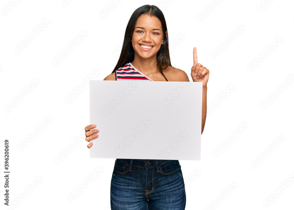 Beautiful hispanic woman holding blank empty banner surprised with an idea or question pointing finger with happy face, number one Beautiful hispanic woman holding blank empty banner surprised with an idea or question pointing finger with happy face, number one