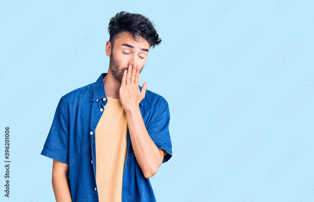 Young hispanic man wearing casual clothes bored yawning tired covering mouth with hand. restless and sleepiness. Young hispanic man wearing casual clothes bored yawning tired covering mouth with hand. restless and sleepiness.