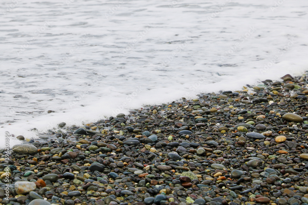Pebble beach and foam from the sea on the background. Pebble beach and foam from the sea on the background.
