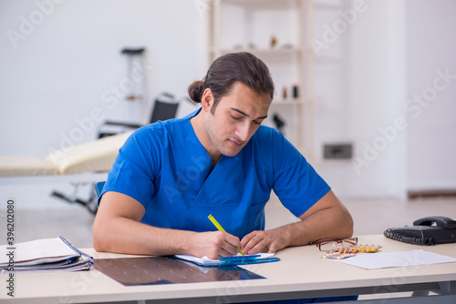 Young male doctor writing prescription in the clinic