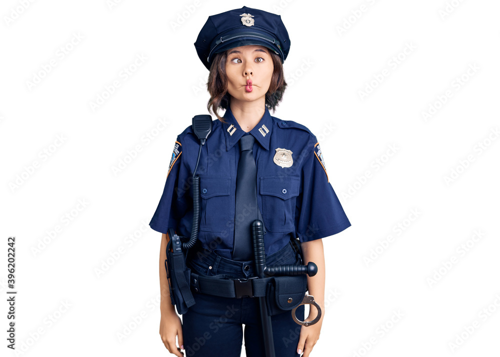 Young beautiful girl wearing police uniform making fish face with lips, crazy and comical gesture. funny expression.