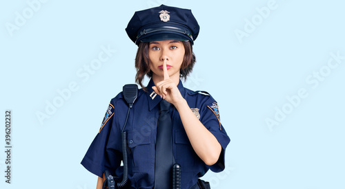 Young beautiful girl wearing police uniform asking to be quiet with finger on lips. silence and secret concept.