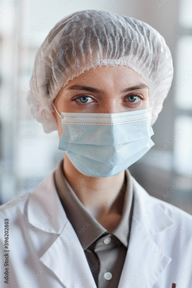 Close up portrait of young female scientist wearing face mask and looking at camera while standing in medical laboratory Close up portrait of young female scientist wearing face mask and looking at camera while standing in medical laboratory