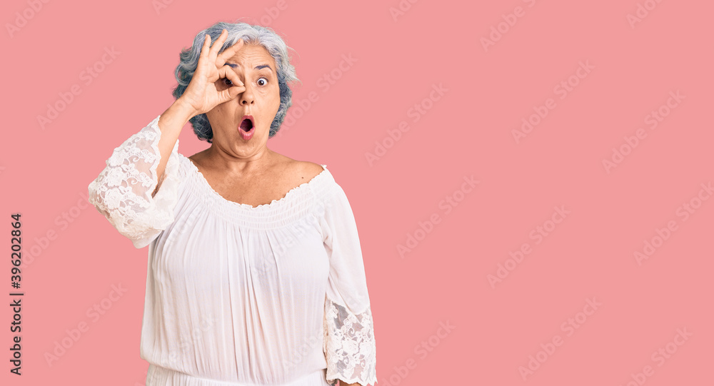 Senior woman with gray hair wearing bohemian style doing ok gesture shocked with surprised face, eye looking through fingers. unbelieving expression. Senior woman with gray hair wearing bohemian style doing ok gesture shocked with surprised face, eye looking through fingers. unbelieving expression.