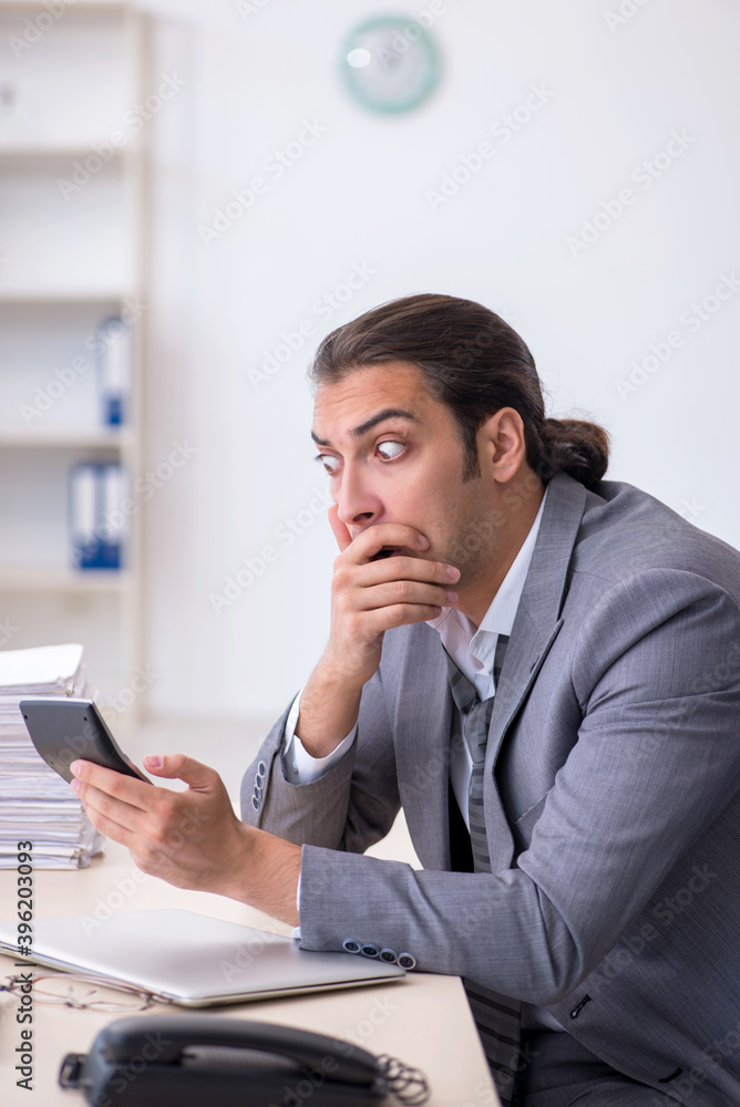 Naklejka premium Young male bookkeeper calculating expences