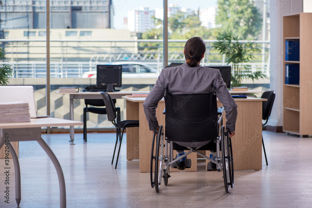 Young male employee in wheel-chair working in the office Young male employee in wheel-chair working in the office