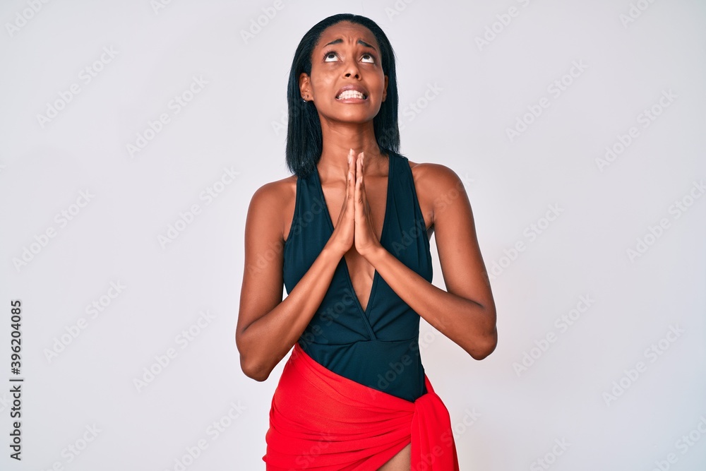 Young african american woman wearing swimsuit begging and praying with hands together with hope expression on face very emotional and worried. begging. Young african american woman wearing swimsuit begging and praying with hands together with hope expression on face very emotional and worried. begging.