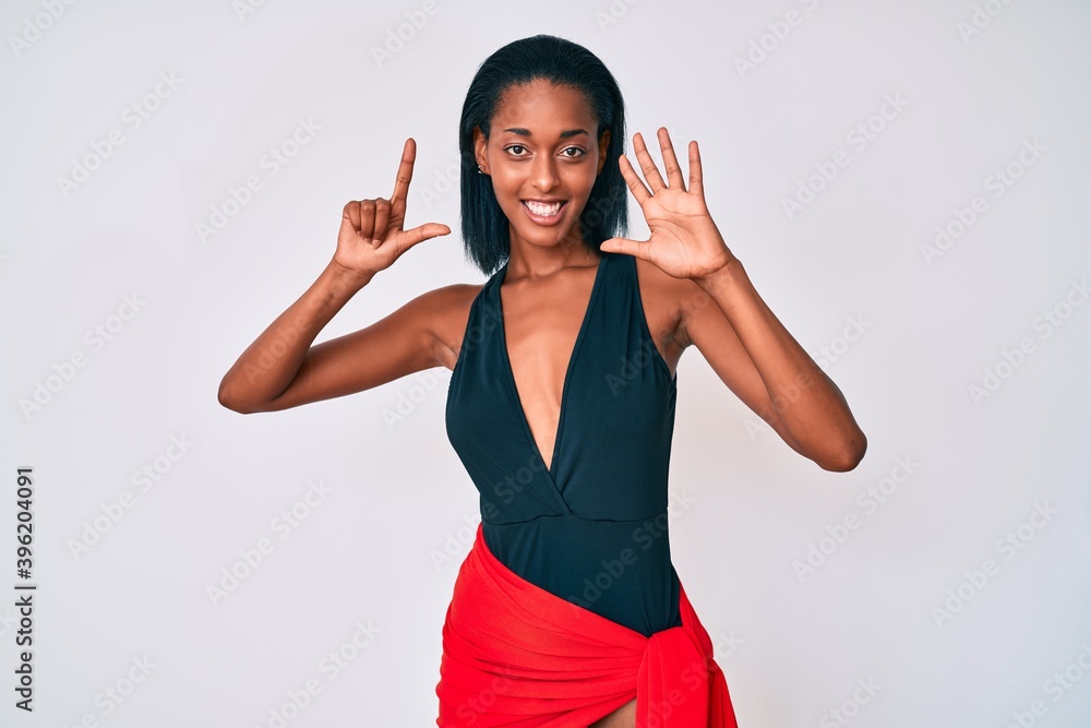 Young african american woman wearing swimsuit showing and pointing up with fingers number seven while smiling confident and happy. Young african american woman wearing swimsuit showing and pointing up with fingers number seven while smiling confident and happy.