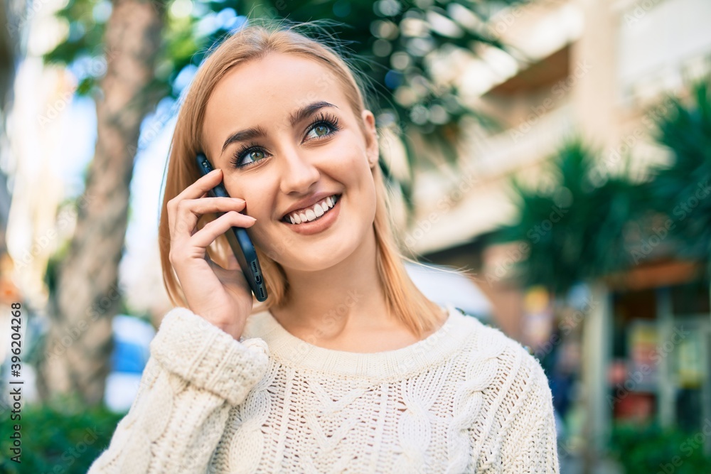 Young blonde girl smiling happy talking on the smartphone at the city. Young blonde girl smiling happy talking on the smartphone at the city.