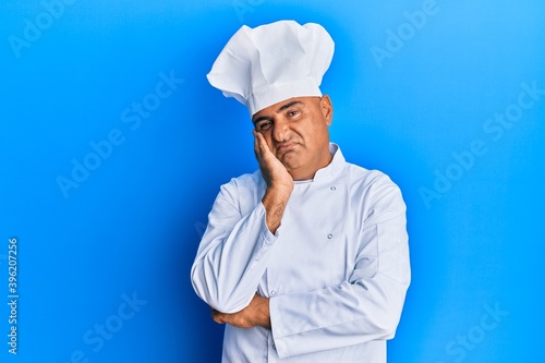 Mature middle east man wearing professional cook uniform and hat thinking looking tired and bored with depression problems with crossed arms.