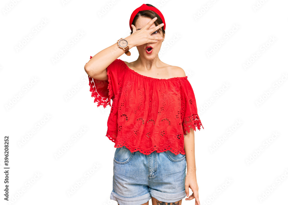 Young brunette woman with short hair wearing casual summer clothes and diadem peeking in shock covering face and eyes with hand, looking through fingers with embarrassed expression. Young brunette woman with short hair wearing casual summer clothes and diadem peeking in shock covering face and eyes with hand, looking through fingers with embarrassed expression.
