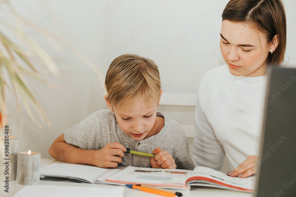 Tutoring. Home schooling. Teacher and pupil. A woman and a blonde boy at the table. Tutoring. Home schooling. Teacher and pupil. A woman and a blonde boy at the table.