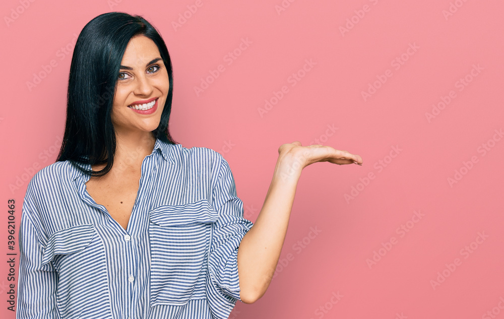 Young caucasian woman wearing casual clothes smiling cheerful presenting and pointing with palm of hand looking at the camera. Young caucasian woman wearing casual clothes smiling cheerful presenting and pointing with palm of hand looking at the camera.